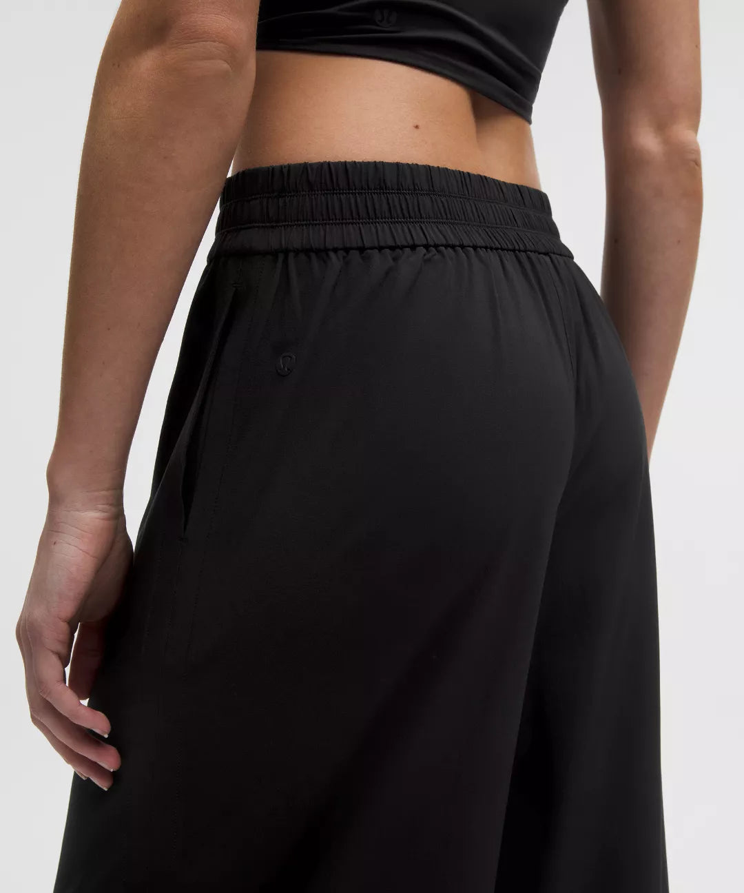 Person wearing black wide-leg pants and a black crop top on a white background
