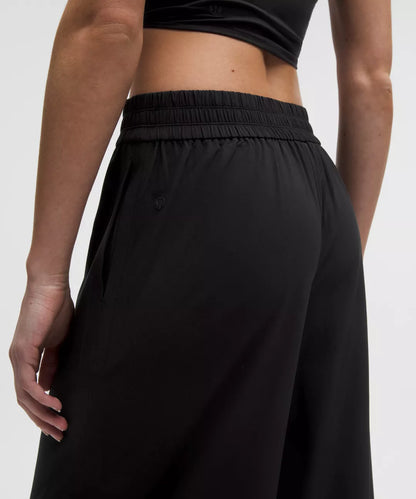 Person wearing black wide-leg pants and a black crop top on a white background