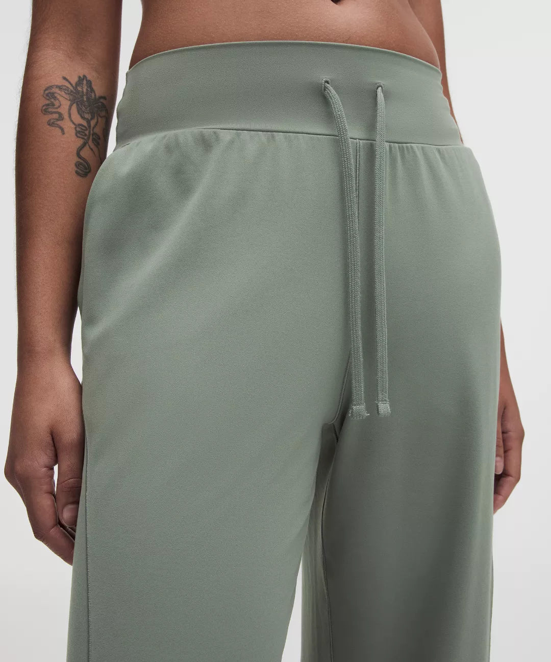 Person wearing light green sweatpants on a white background