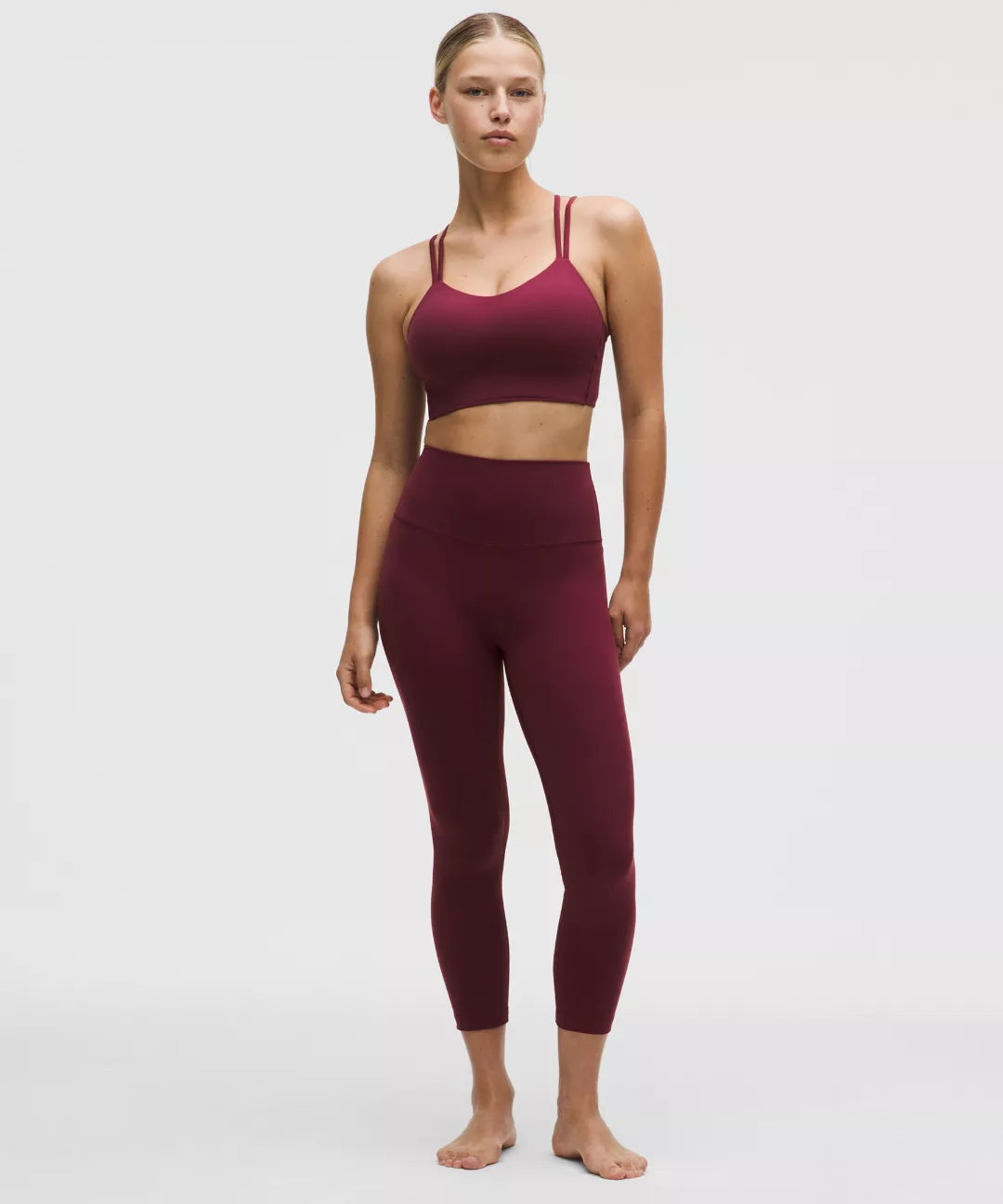 Woman wearing a burgundy sports bra and leggings on a white background