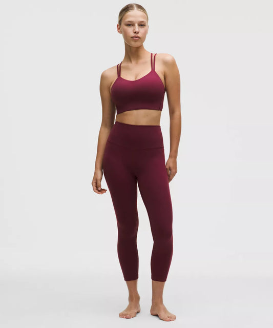 Woman wearing a burgundy sports bra and leggings on a white background
