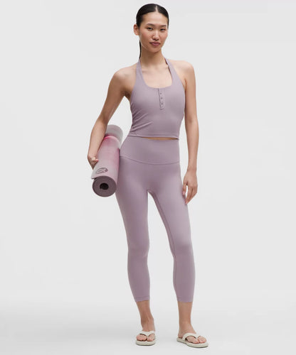 Woman in lavender athletic wear holding a yoga mat on a white background