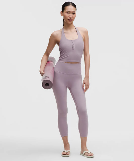 Woman in lavender athletic wear holding a yoga mat on a white background