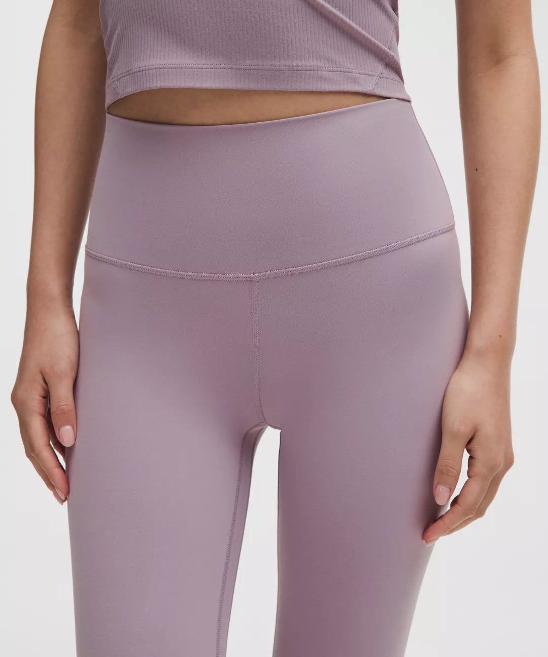 Person wearing a pair of mauve leggings on a plain background