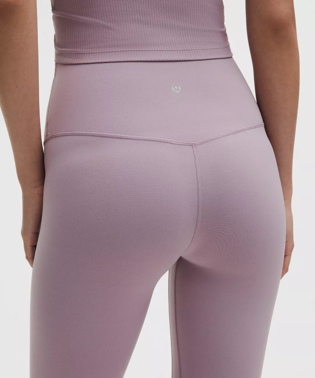 Person wearing a fitted lavender athletic outfit on a plain background
