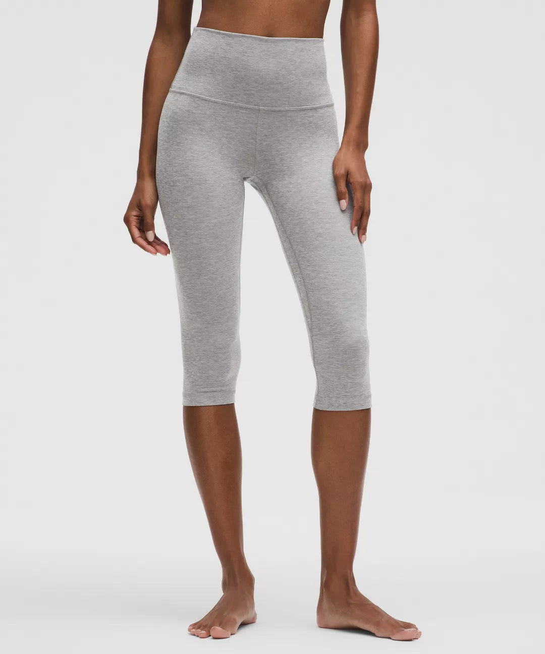 Person wearing gray capri leggings on a white background