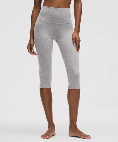 Person wearing gray capri leggings on a white background