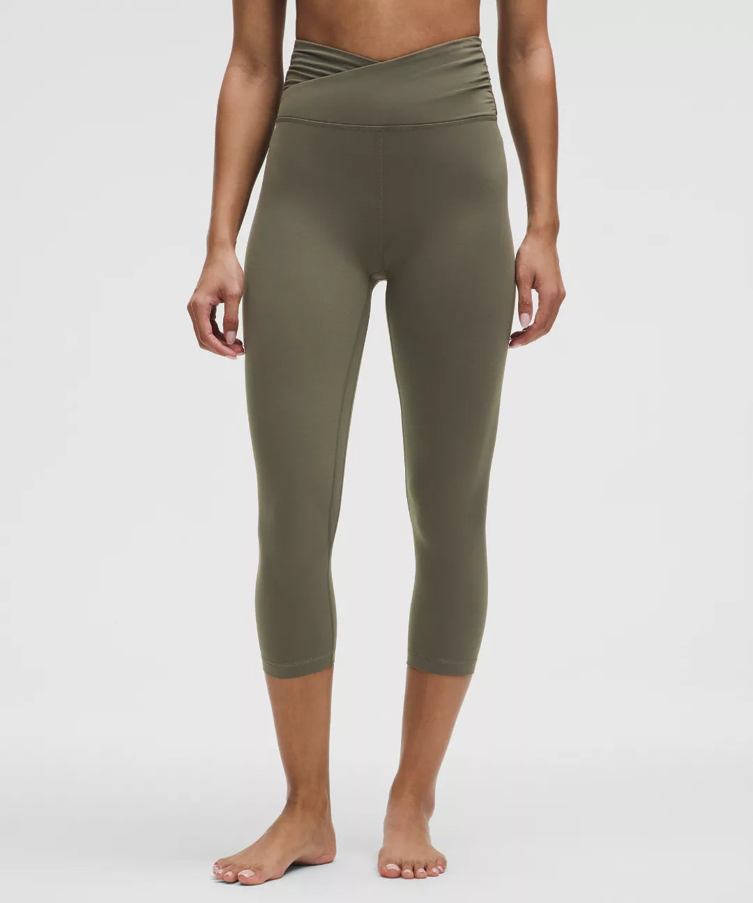 Person wearing olive green leggings on a white background