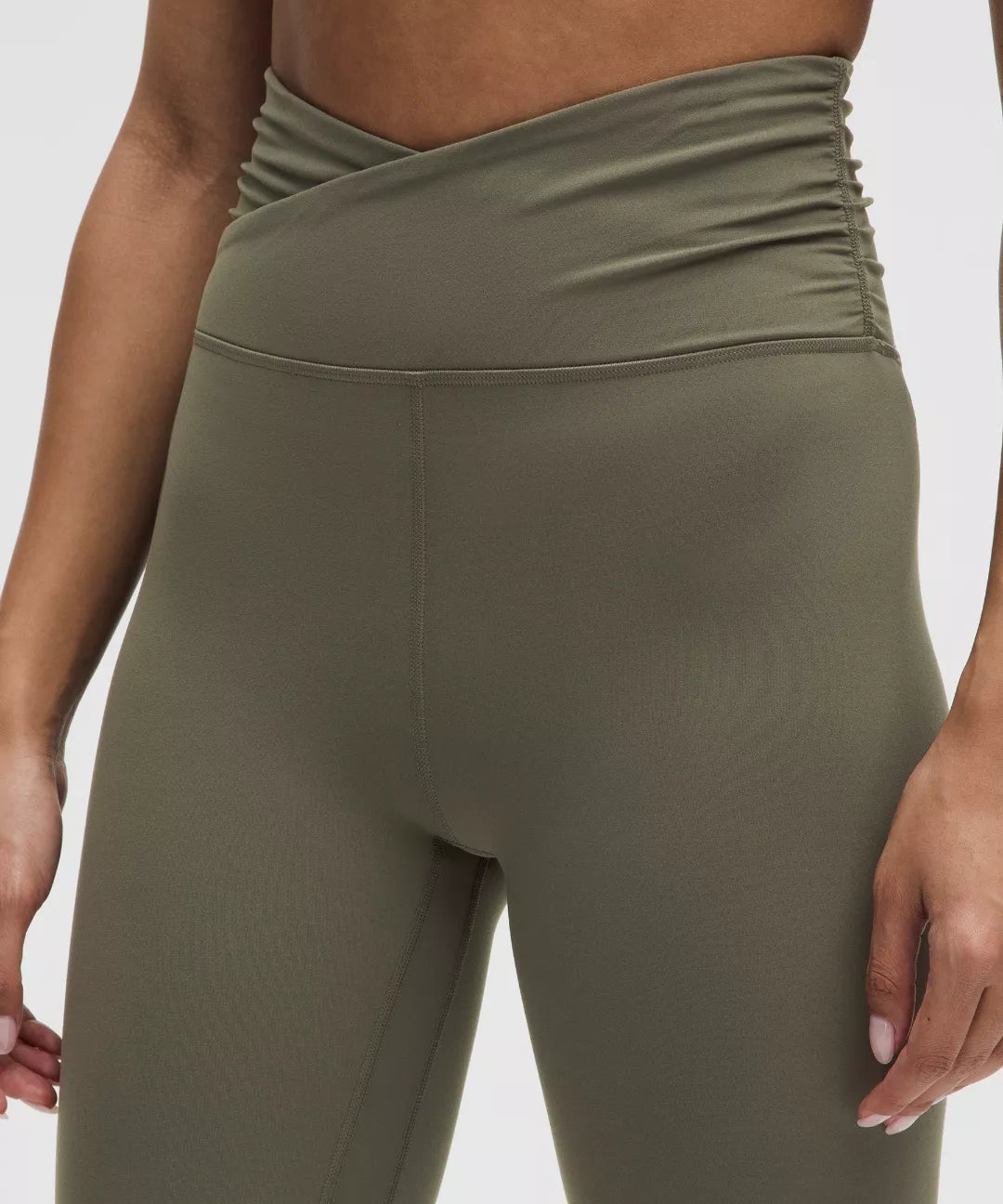 Olive green leggings worn by a person on a white background
