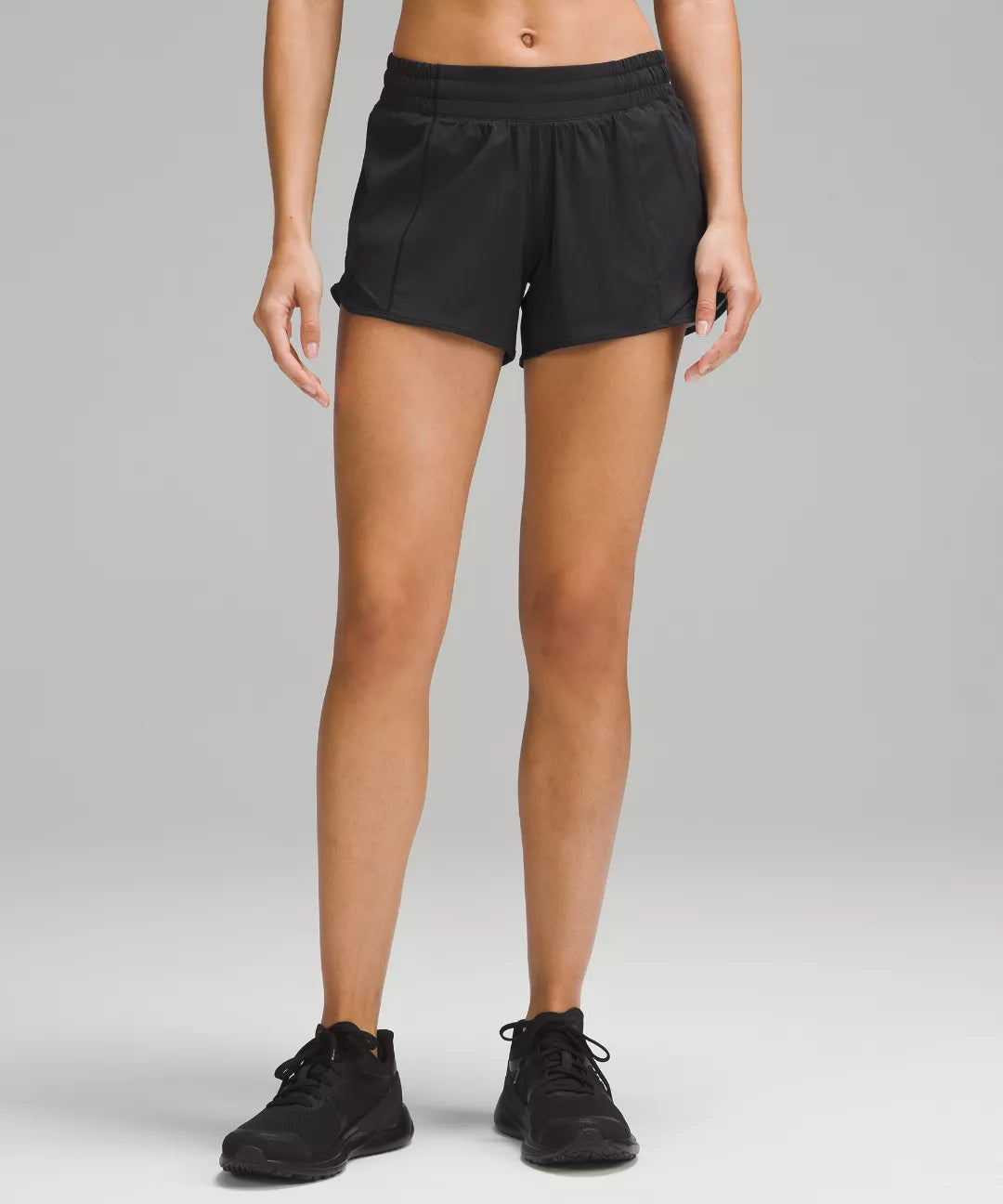 Person wearing black shorts on a gray background
