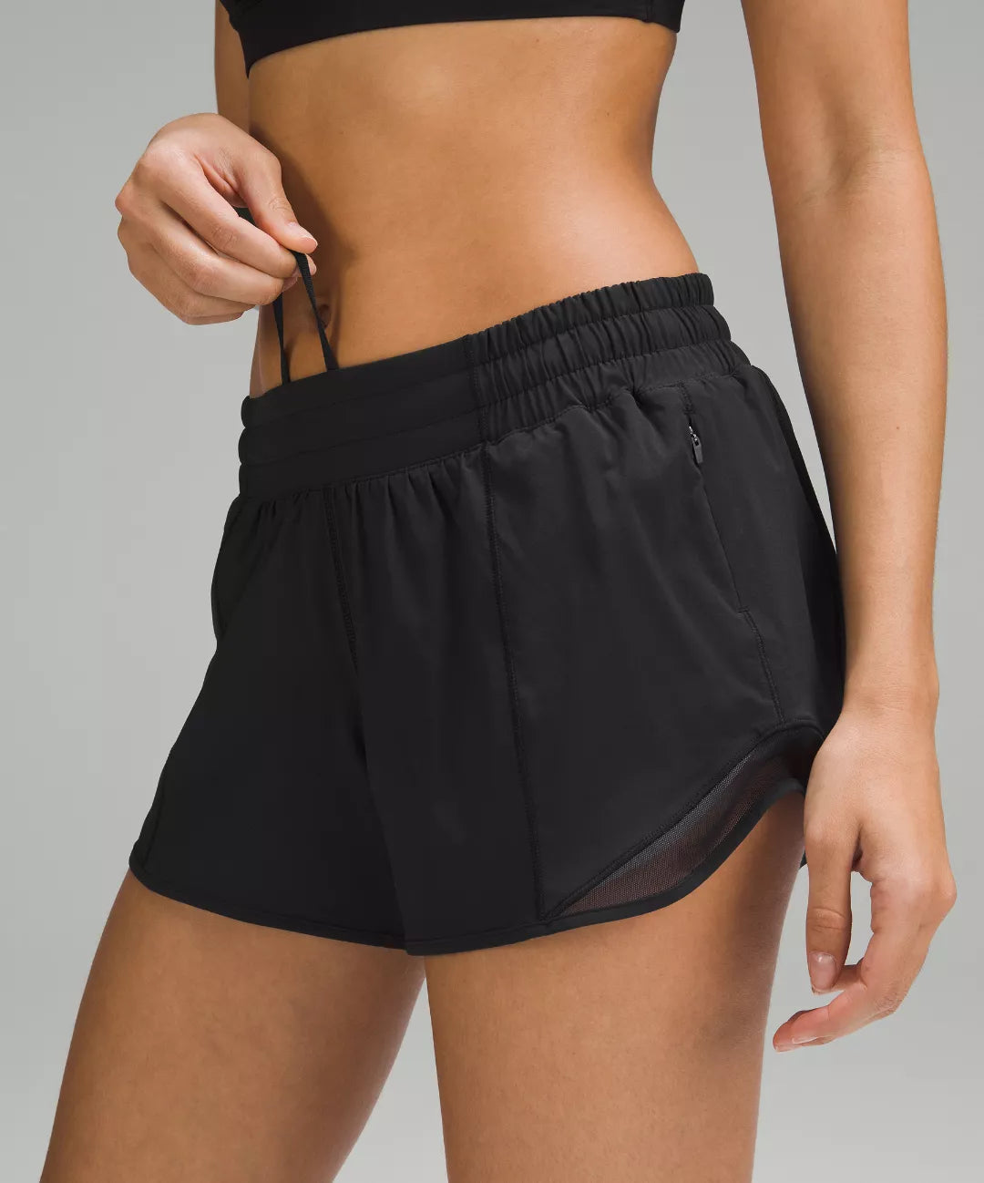 Black athletic shorts worn by a person on a gray background