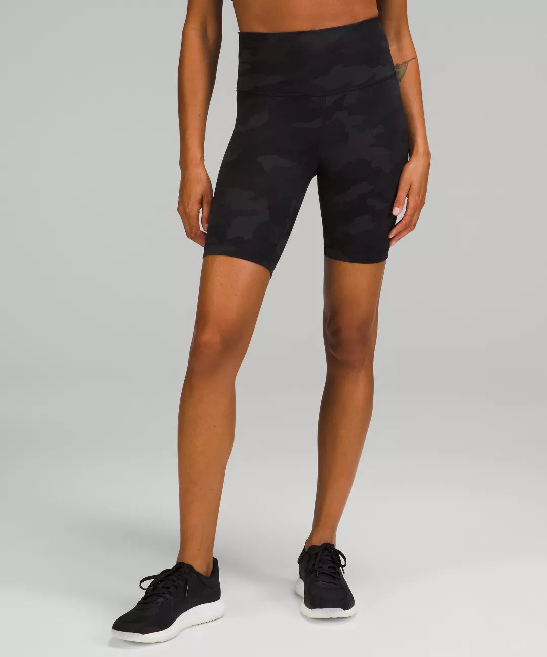 Person wearing black athletic shorts on a gray background