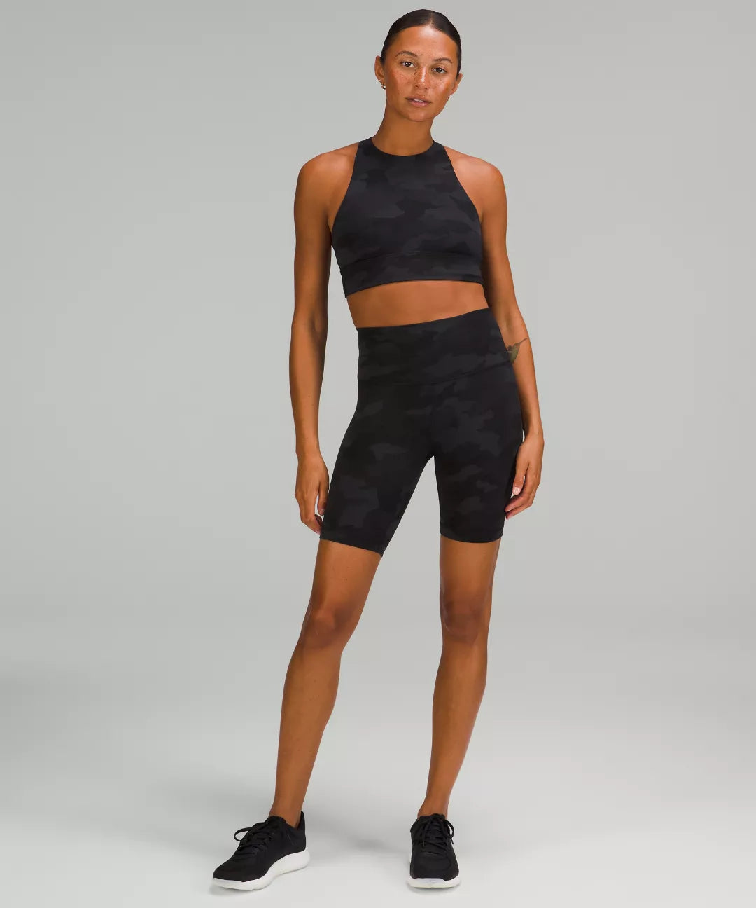 Woman wearing a black athletic outfit on a gray background