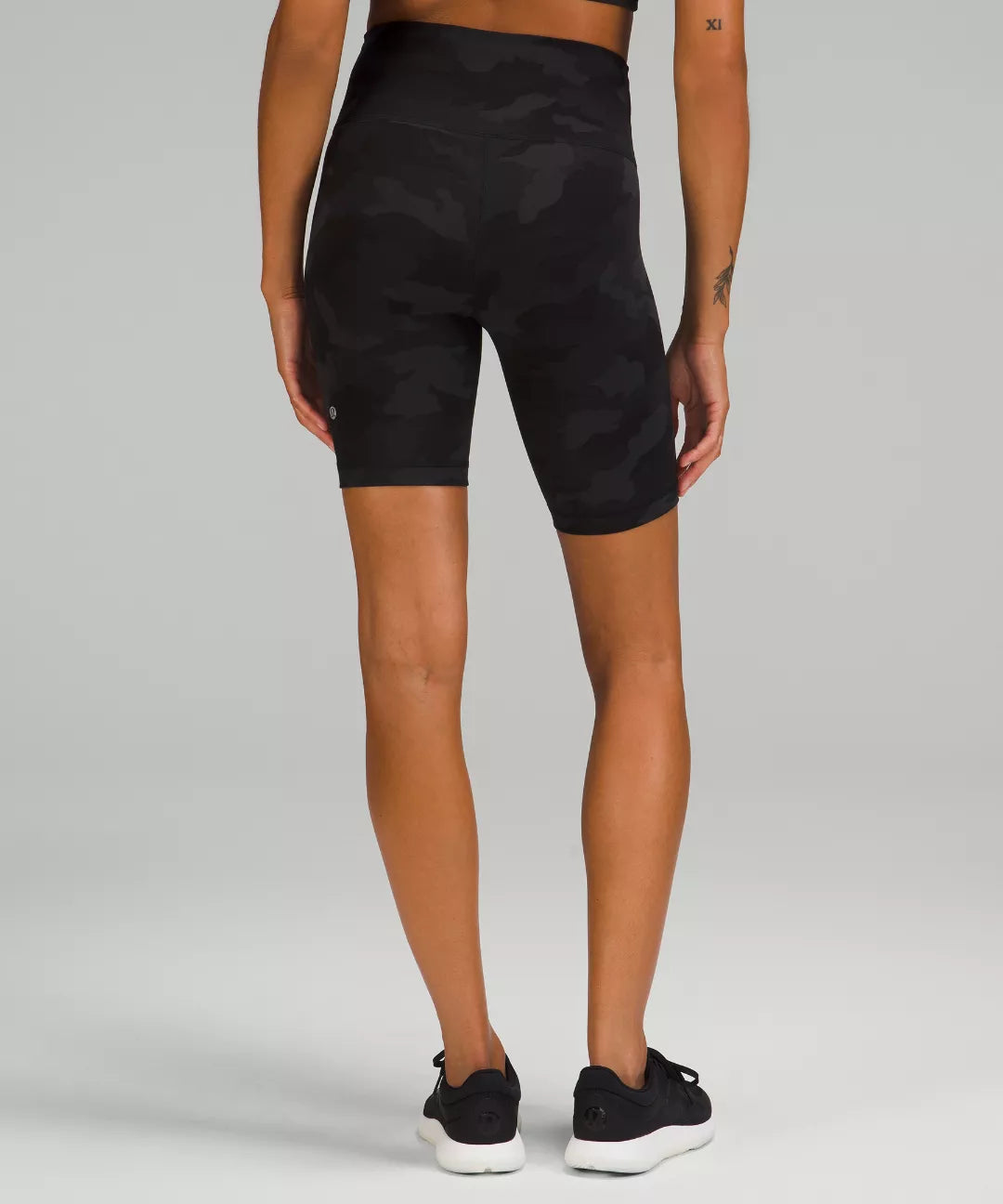 Person wearing black patterned shorts on a plain background