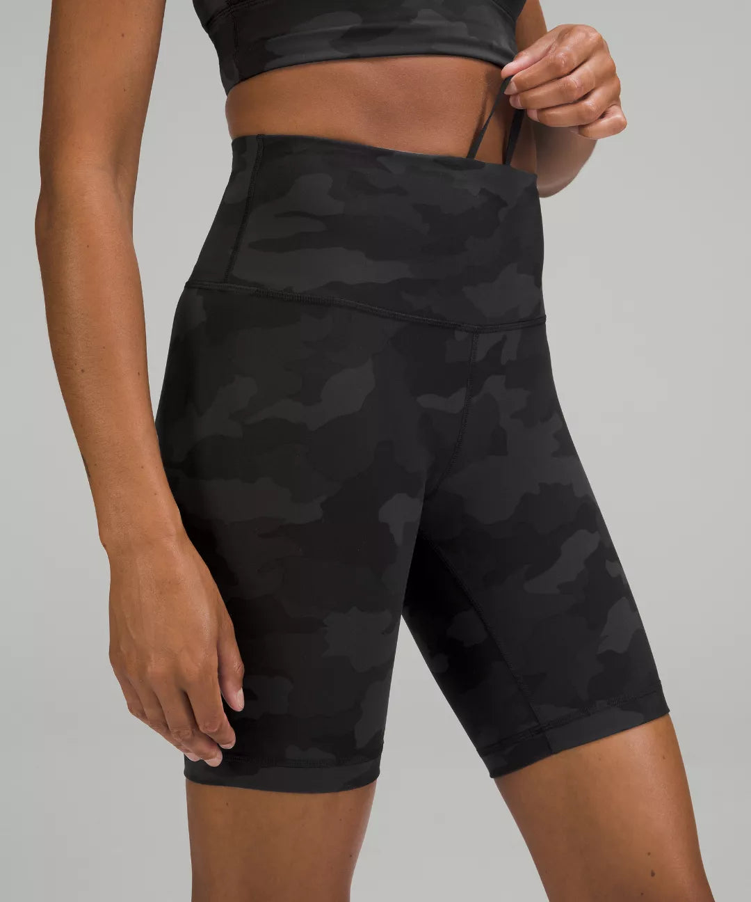 Black camouflage athletic shorts worn by a person on a gray background