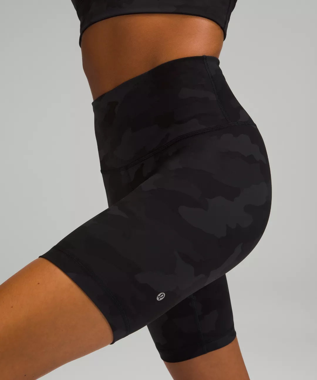 Black camouflage shorts worn by a person on a gray background