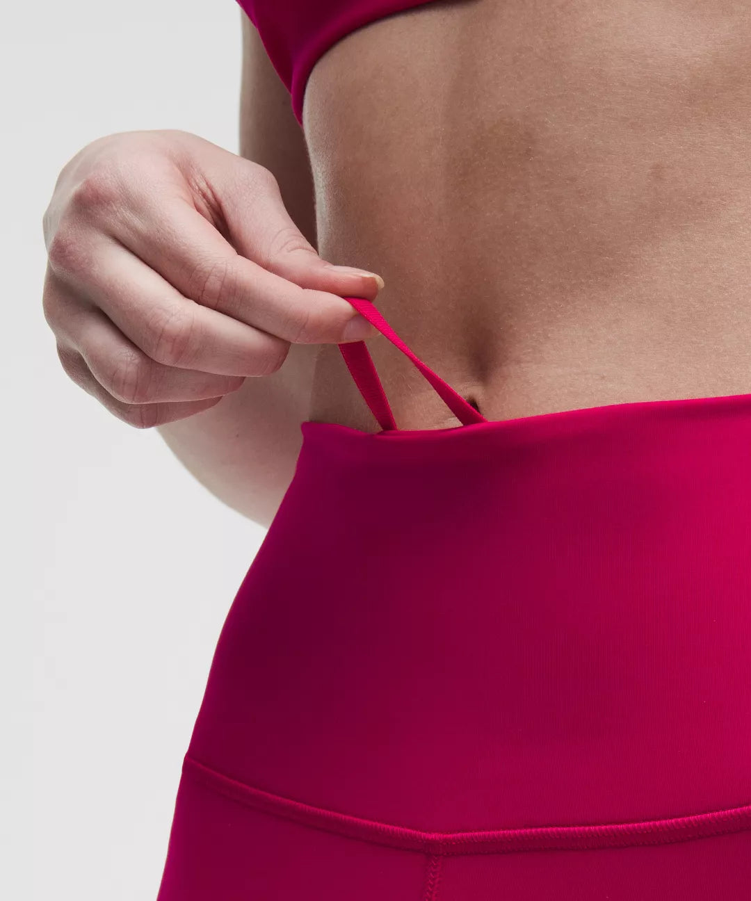Close-up of a person wearing a bright pink bikini top with a neutral background