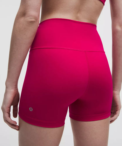 Person wearing bright pink athletic shorts on a plain background