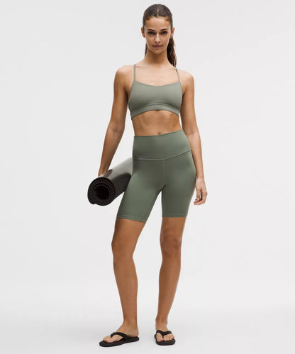 Woman in green athletic wear holding a yoga mat on a white background