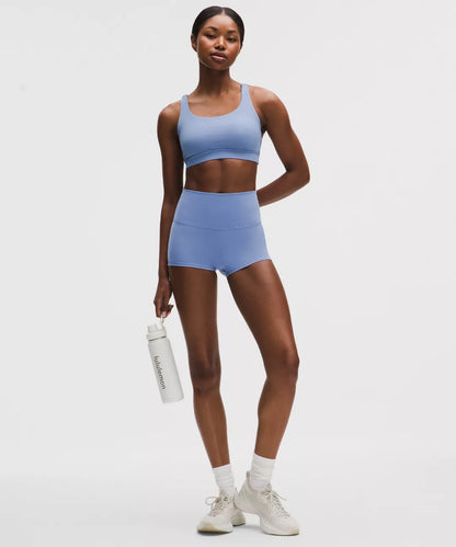 Woman wearing a blue athletic outfit holding a water bottle on a white background