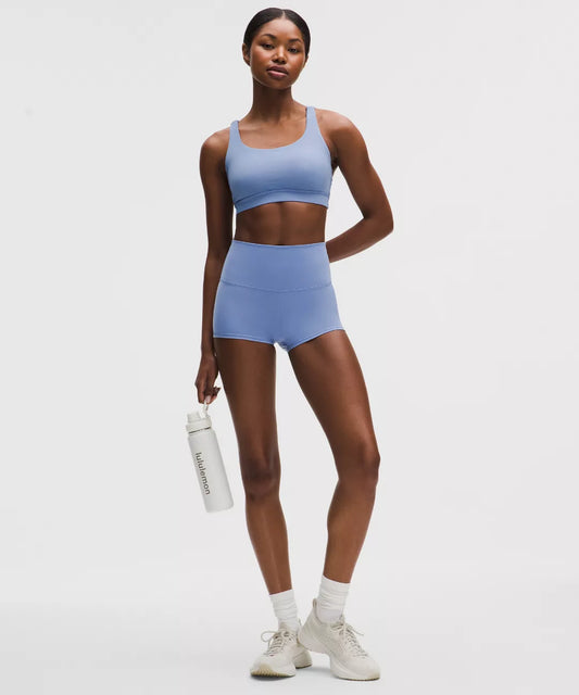 Woman wearing a blue athletic outfit holding a water bottle on a white background