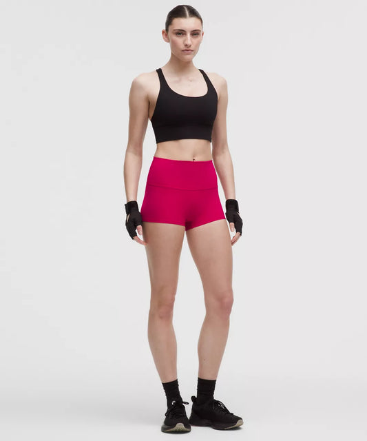 Person wearing a black sports bra and pink shorts on a white background