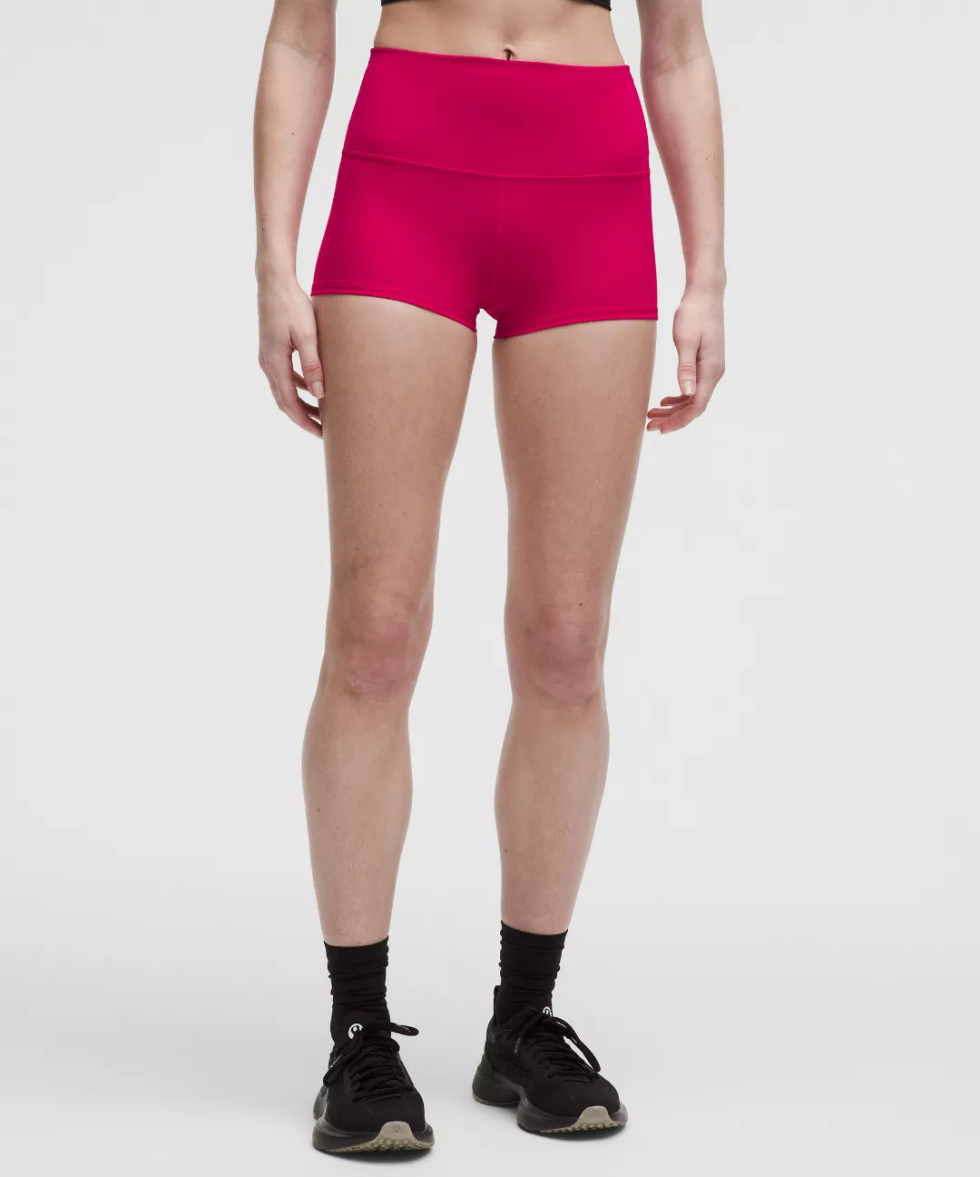 Person wearing bright pink athletic shorts on a white background