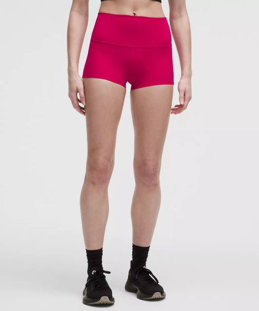 Person wearing bright pink athletic shorts on a white background