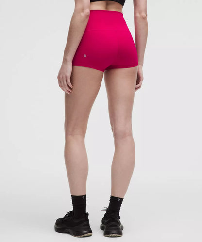 Person wearing bright pink high-waisted shorts on a white background