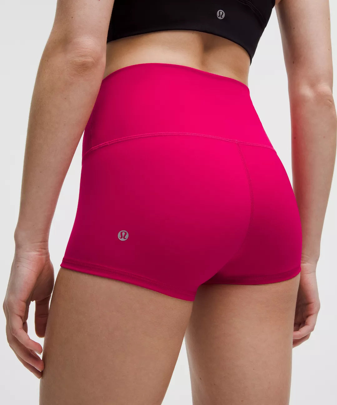 Person wearing bright pink athletic shorts with a white background