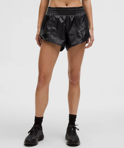 Person wearing black shiny shorts on a white background
