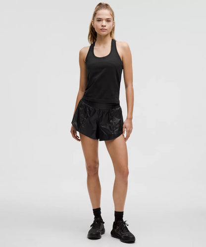 Woman wearing a black tank top and shorts on a white background