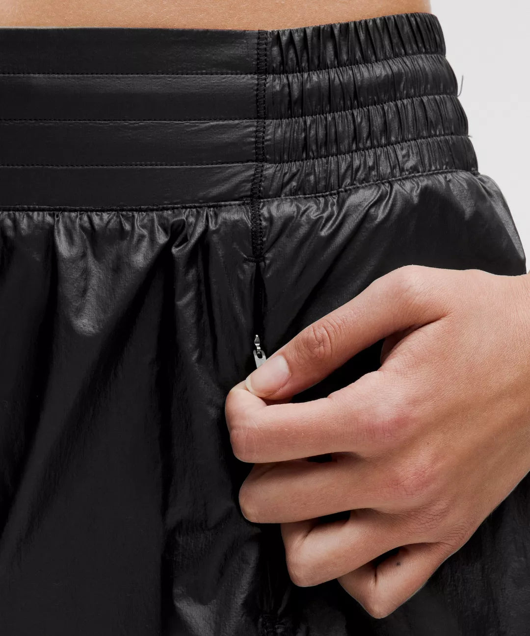 Close-up of a person adjusting a black jacket with a zipper.