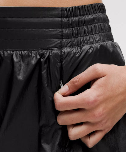 Close-up of a person adjusting a black jacket with a zipper.