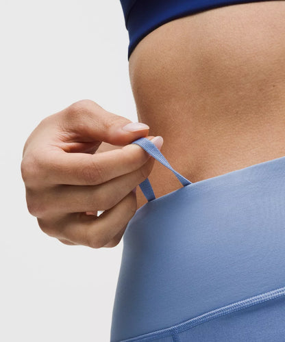 Person adjusting a blue sports bra strap against a neutral background