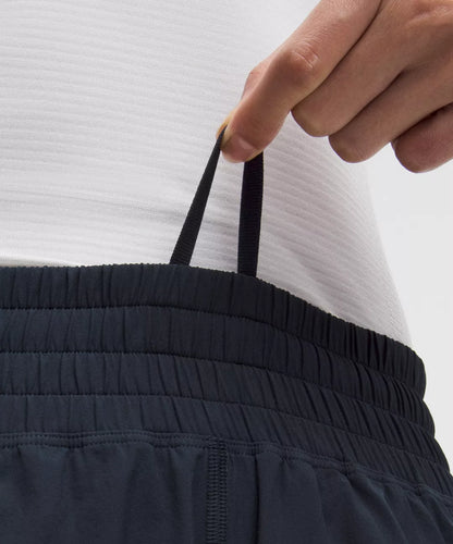 Person wearing dark blue pants with a white shirt, focusing on the waistband.