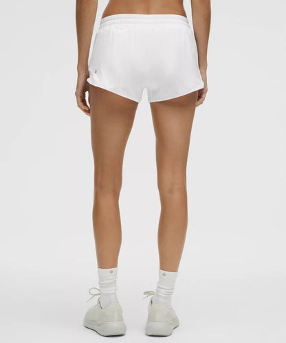 Person wearing white shorts and white sneakers on a plain background