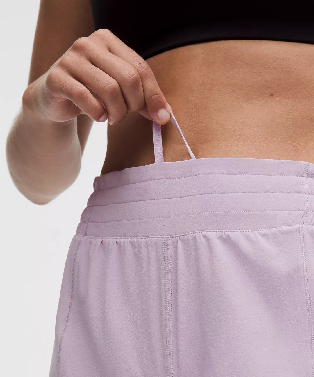 Person wearing a black top and light purple shorts with a neutral background