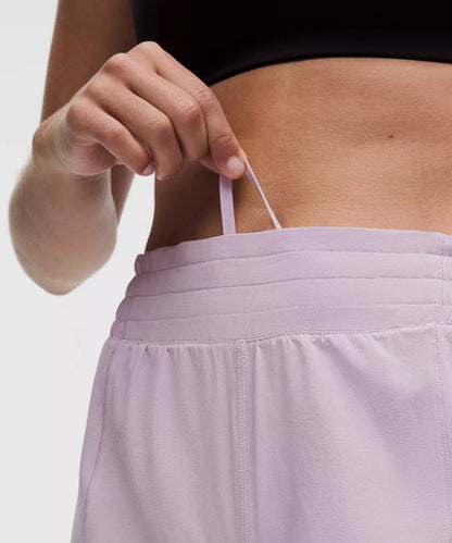 Person wearing a black top and light purple shorts with a neutral background