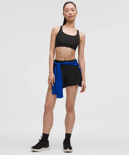 Woman wearing a black sports bra and shorts with a blue wrap on a white background