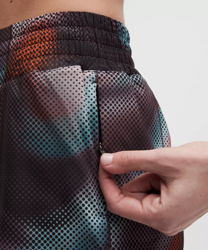 Close-up of a person wearing a colorful patterned shorts with a hand adjusting the waistband.