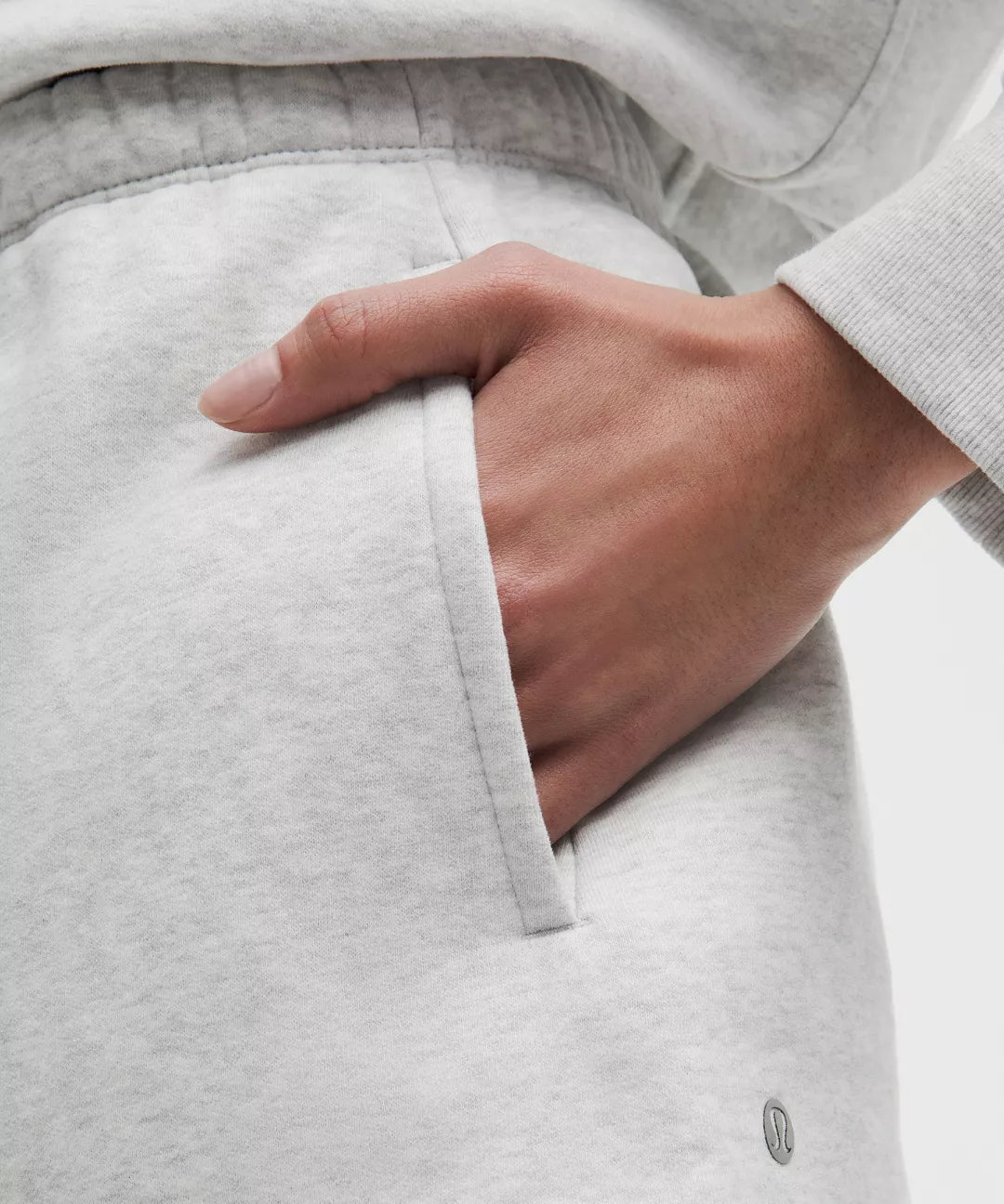 Close-up of a hand in a light gray sweatshirt pocket with a blurred background