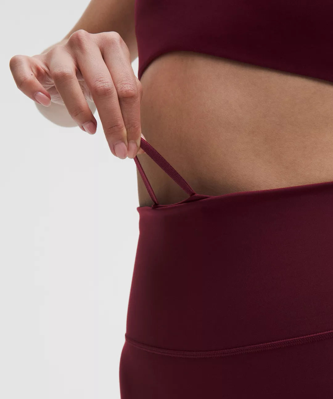 Maroon athletic outfit with a focus on the waistband against a neutral background