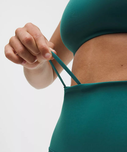 Person wearing a green bikini top with a neutral background