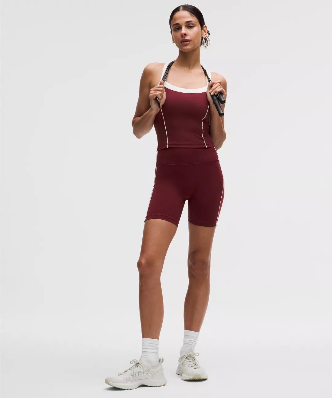 Woman wearing a maroon athletic outfit on a white background