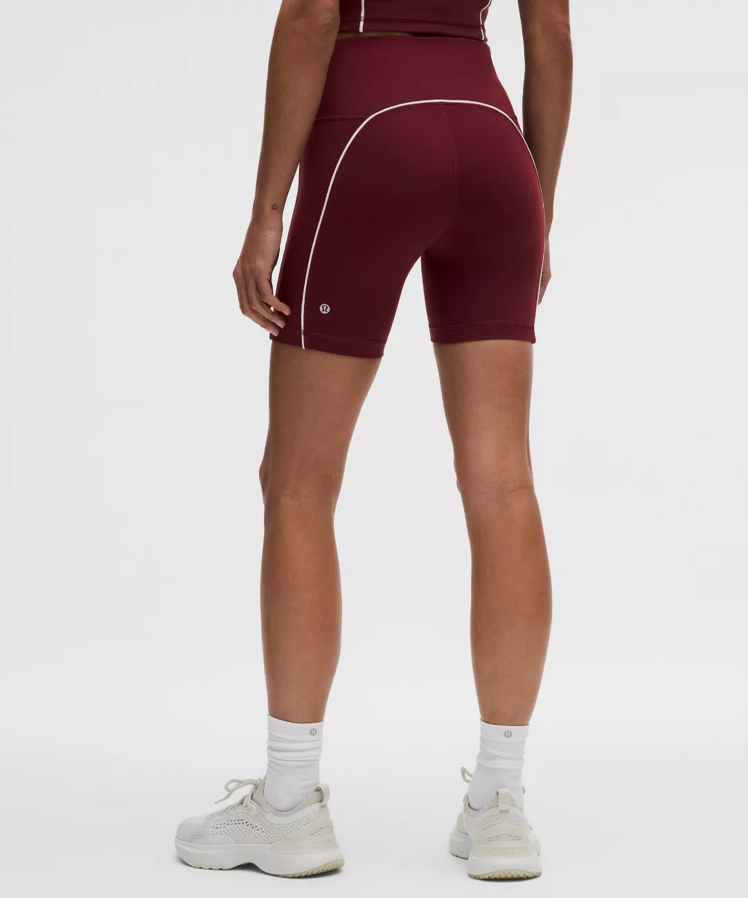 Maroon athletic shorts with white piping worn by a person on a white background
