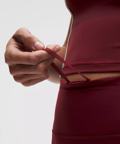 Person adjusting a red dress strap against a neutral background