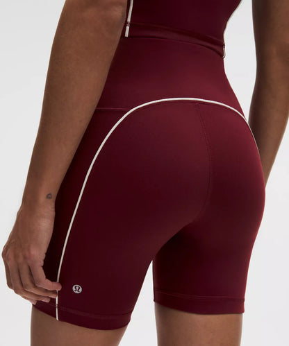 Maroon athletic shorts with white piping on a neutral background