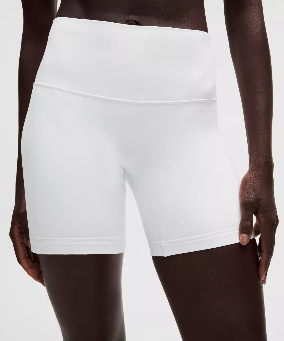 White athletic shorts worn by a person on a white background