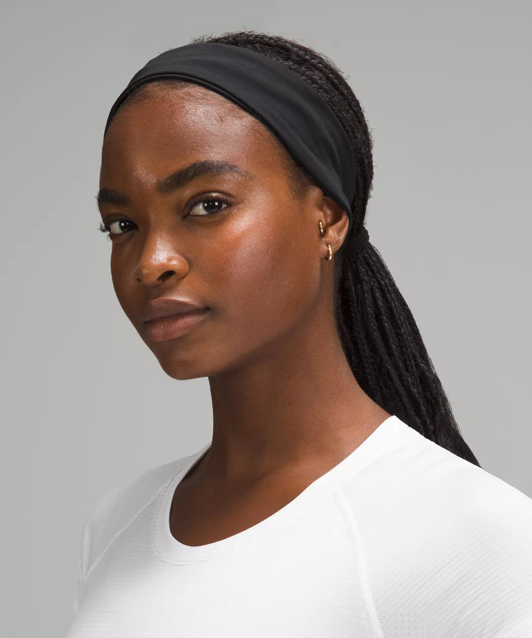 Woman wearing a black headband with braided hair against a gray background